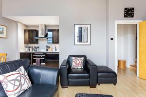 a living room with a couch and a chair and a kitchen at Chic Farringdon Flat in London