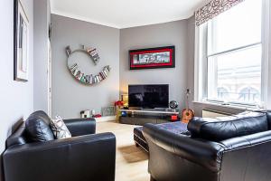 ein Wohnzimmer mit 2 Ledersesseln und einem TV in der Unterkunft Chic Farringdon Flat in London