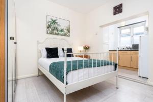 a bedroom with a white bed with a green blanket at Studio Flat 3, 20 mins to Central London in The Hyde