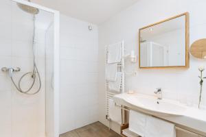 a white bathroom with a sink and a mirror at Hotel Kögele mit Restaurant bei Innsbruck Axamer Lizum in Innsbruck