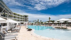 Una piscina de resort con mesas, sillas y sombrillas. en WaterColor Inn & Resort, en Santa Rosa Beach