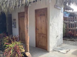 zwei Holztüren an der Seite eines Hauses in der Unterkunft Tres Palmas in Montañita