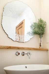 um espelho numa parede acima de um lavatório na casa de banho em 　白馬　コテージ　チェスナッツ em Hakuba