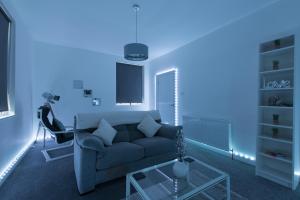 a living room with a couch and a blue light at Luxe Maisonette- Parking, 4K TVs, LEDs, Local Snacks and more! in Bath