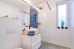 a white bathroom with a sink and a shower at FEEL HOME DeLuxe CORVIN -FREE PARKING-AC-Elevator in Budapest