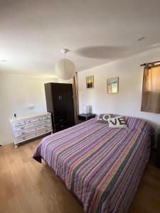 1 dormitorio con 1 cama con edredón a rayas en Casita Santa Ana Miramar Buenos Aires en Miramar