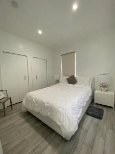 a white bedroom with a large white bed and wooden floors at Modern & New,Excellent Location Miami in Miami