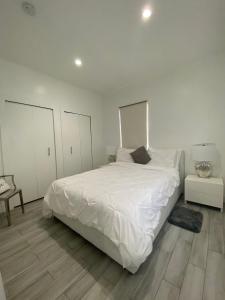 um quarto branco com uma grande cama branca e pisos em madeira em Modern & New,Excellent Location Miami em Miami