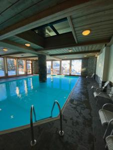 a large swimming pool with chairs in a building at Plagne Villages, Charmante Résidence de Tourisme 4 Etoiles in Plagne Villages