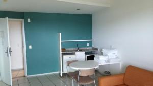 eine Küche mit einem weißen Tisch und einer blauen Wand in der Unterkunft Bristol Praia do Canto Apart Hotel in Vitória