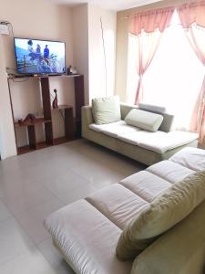 ein Wohnzimmer mit einem Sofa und einem TV in der Unterkunft Dulce Hogar in Loja