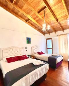 two beds in a room with wooden ceilings at Hotel Feimar in Cusco