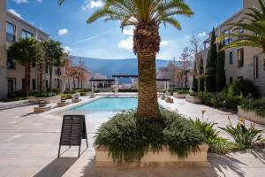 a palm tree in a courtyard with a swimming pool at Paloma Apartment - Portonovi Resort in Herceg-Novi