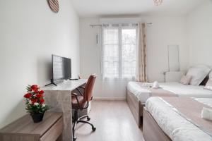 1 dormitorio con 2 camas y escritorio con ordenador en Cozy - Free Parking - 15mn from Paris Montparnasse en Clamart