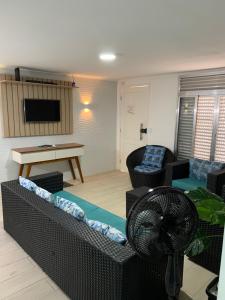 a living room with a couch and a fan at Apartamento Praia Enseada Guarujá Wilma - próximo da praia - com ar condicionado e vaga para carro in Guarujá