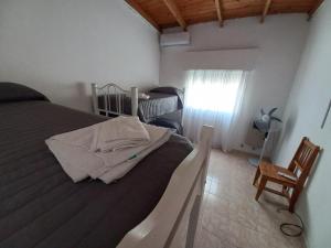 um quarto com uma cama, uma cadeira e uma janela em Alojamientos Litoral - Casa del Sol em Gualeguaychú