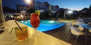 a drink on a table next to a swimming pool at Naiades Villas in Kato Achaia