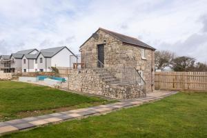 a stone house in a yard with a fence at Cornwall - Unique two storey barn in St Austell
