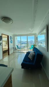 Hermoso Apto Excalibur Rodadero في سانتا مارتا: غرفة معيشة مع أريكة زرقاء في غرفة مع نوافذ