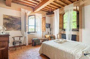sypialnia z łóżkiem i stołem oraz 2 oknami w obiekcie Villa San Filippo w Arezzo