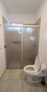 a bathroom with a toilet and a glass shower at Hermoso condominio con alberca en Puerto Morelos in Puerto Morelos