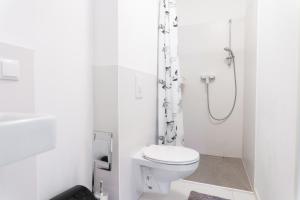 a white bathroom with a toilet and a shower at Apartment Hotel Triester in Vienna
