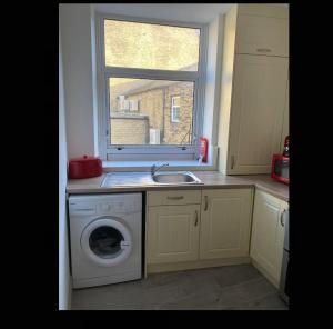 a kitchen with a washing machine and a window at The Willows in Brighouse