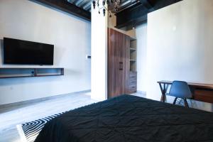 een slaapkamer met een bed, een bureau en een televisie bij Elegante LOFT 6 con vista a la ciudad in Mexico-Stad