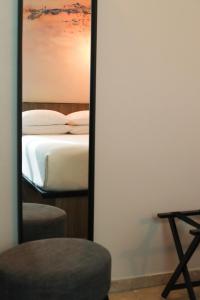 a mirror in a bedroom with a bed and a chair at The Tryst Beachfront Hotel in San Juan