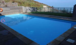 a large swimming pool with blue water in a yard at Curlew 3 - The Cove in Brixham