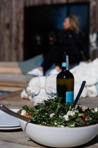 a bowl of salad and a bottle of wine on a table at Pool Spa Sauna and Beach Beddingestrand in Beddinge Strand