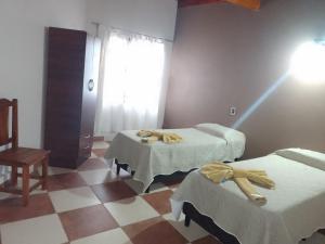 a room with two beds and a chair and a window at Hotel El Jardin Dante in Tilcara