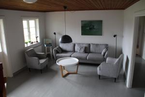 a living room with a couch and two chairs and a table at Villa Lägervik Vitsand in Gunsjögården
