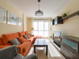 een woonkamer met een oranje bank en een televisie bij Mahostly Apartamento Castillo in Puerto del Rosario