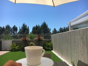 a cup of coffee sitting on a table next to a fence at Front Beach Villa Cabedelo in Viana do Castelo