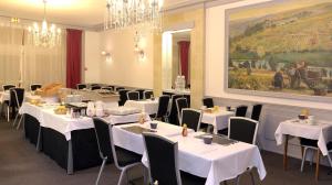 a dining room with white tables and chairs and a painting at Hôtel De France in Angers