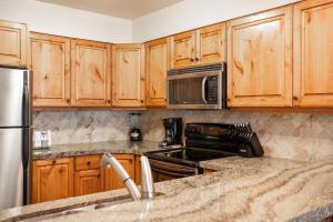 eine Küche mit Holzschränken und Geräten aus Edelstahl in der Unterkunft SNOW FLOWER 149 condo in Park City + 38 Fotos
