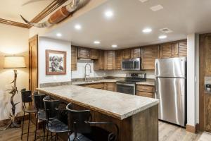 una cucina con mobili in legno e un frigorifero in acciaio inossidabile di PARK STATION 229 condo a Park City