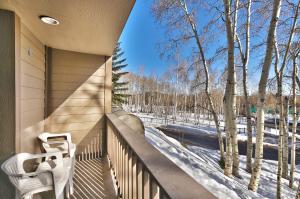 a balcony with two chairs and a view of snow covered trees at SNOW FLOWER 104 condo in Park City