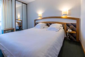 una camera da letto con un grande letto bianco con due cuscini di Best Western Le Relais de Laguiole Hôtel & Spa a Laguiole