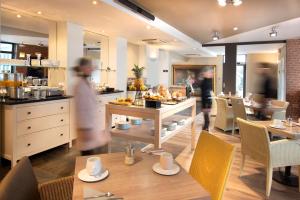 una persona caminando por un restaurante con mesa y sillas en Best Western Plus Hotel Kregenn, en Quimper