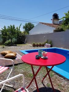 una mesa roja con una bebida junto a una piscina en La Soñadita en Salta
