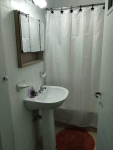 y baño blanco con lavabo y ducha. en Departamento en Mendoza Capital en Mendoza