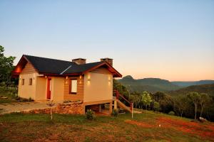 a house on a hill with the sunset in the background at Parador São João in Canela