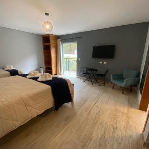 a hotel room with two beds and a flat screen tv at Pousada Alpes Azul in Campos do Jordão