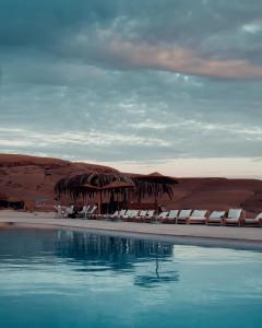 a view of a beach with chairs and a swimming pool at Alkamar Camp Agafay in El Karia