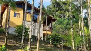 a house in the middle of some palm trees at Chalé Rio dos Meros in Paraty