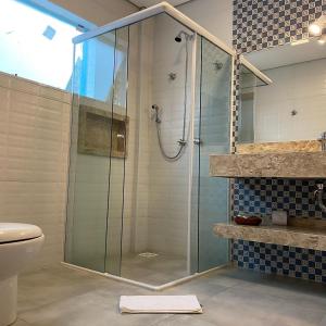 La salle de bains est pourvue d'une douche avec une porte en verre. dans l'établissement Pousada Alpes Azul, à Campos do Jordão