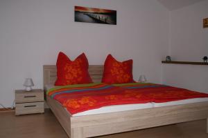 1 dormitorio con cama de madera y almohadas rojas en Ferienwohnung Angela, en Neuenkirchen