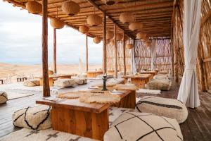 a restaurant in the desert with tables and chairs at Alkamar Camp Agafay in El Karia